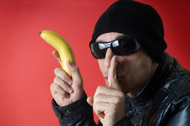 Efeito Halo é o perigo oculto dos vieses Robber holding a banana in his hand in place of a gun and making silence gesture.